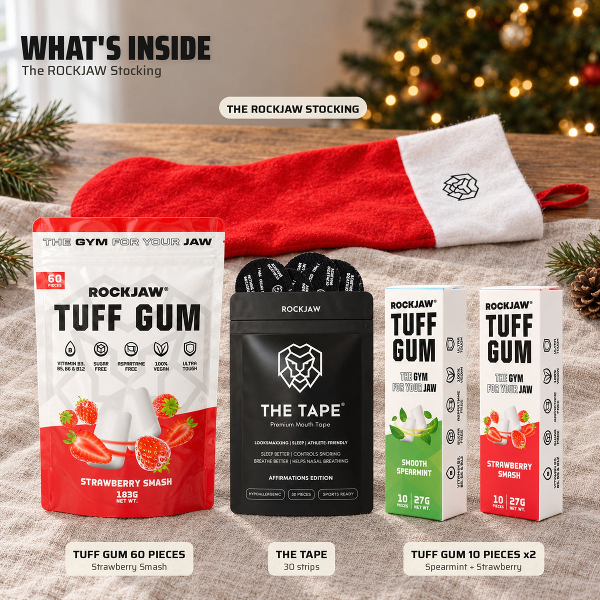 What's inside the ROCKJAW Stocking: a Tuff Gum 60 piece Strawberry Smash pouch, The Tape 30 strips, a Tuff Gum Smooth Spearmint pack and a Tuff Gum Strawberry Smash pack, laid out on linen in front of the empty stocking and a Christmas tree.